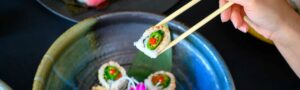 Sushi on a plate with a hand picking up a piece
