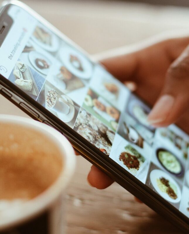 Person with phone in hand displaying the Instagram app next to a cup of coffee.