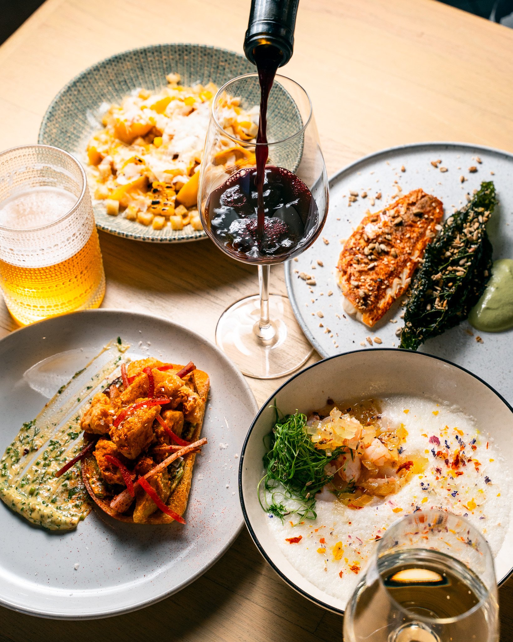Bottle of wine being poured on table surrounded by food.